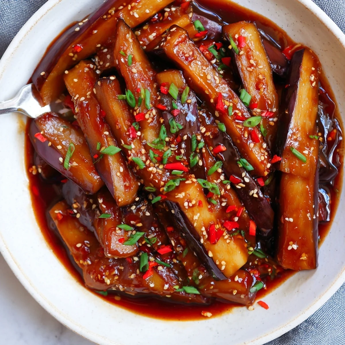 Sichuan Style Braised Aubergines glistening in spicy red sauce over steamed rice