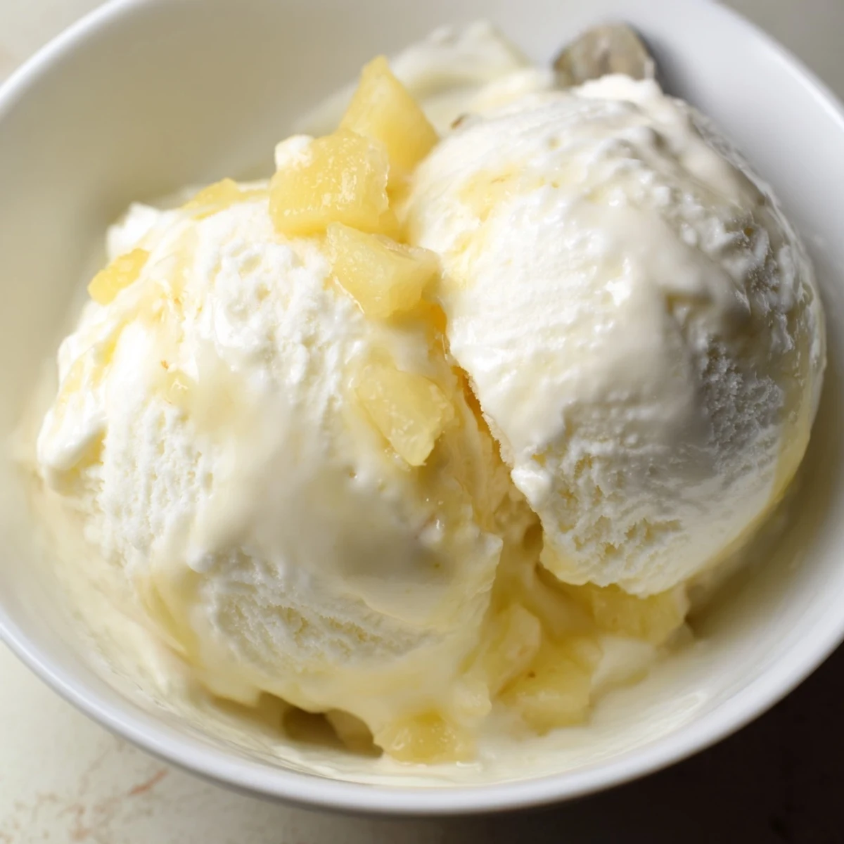 Creamy Pineapple Ice Cream served in a bowl with toasted coconut flakes