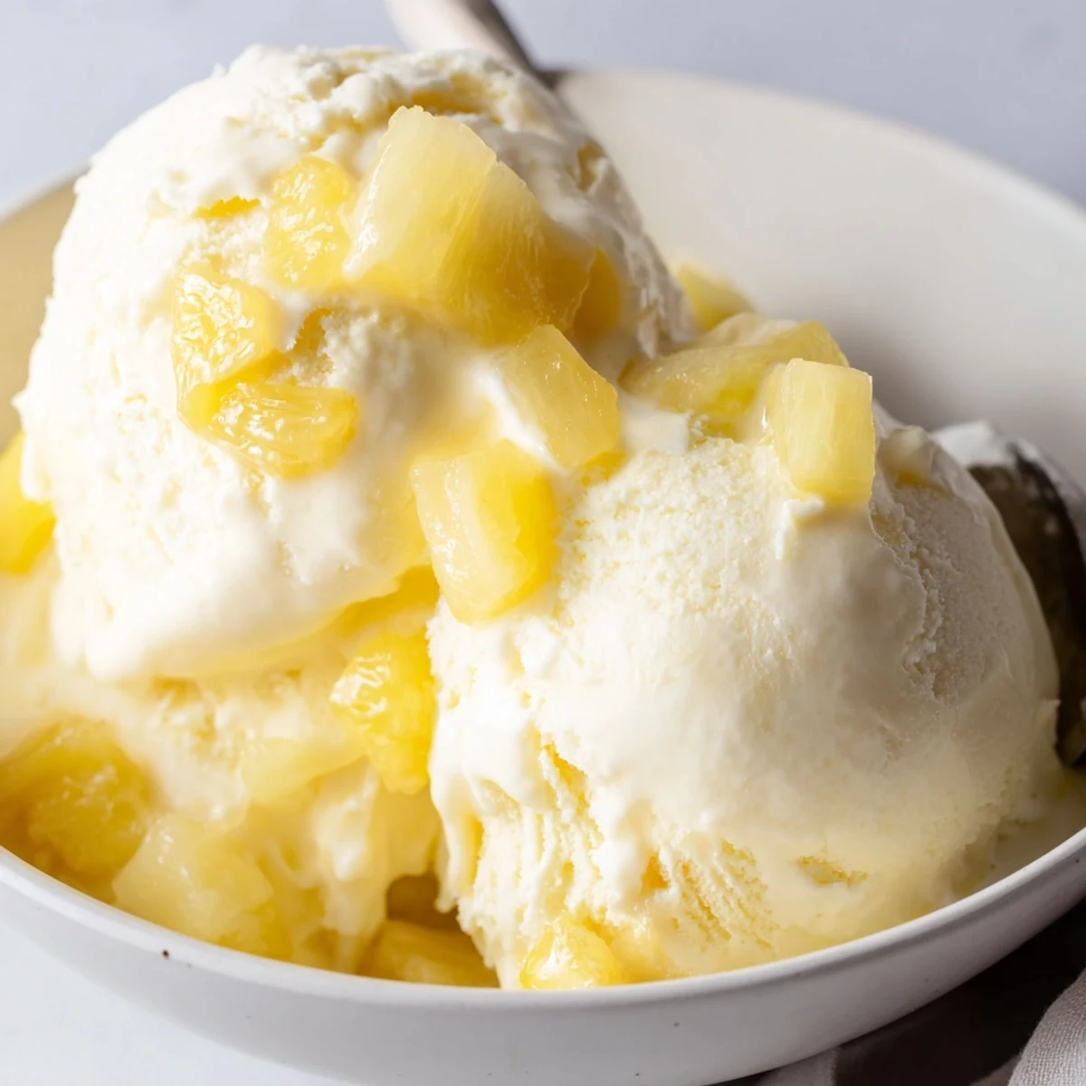 A scoop of Creamy Pineapple Ice Cream glistening, tropical aroma, soft texture