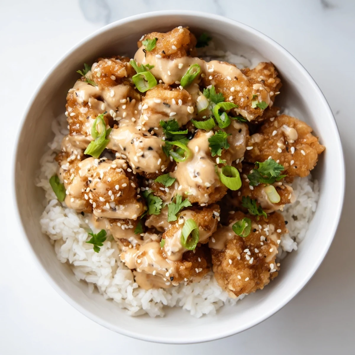 Vibrant bowl featuring crunchy bang bang chicken with cucumber carrot cabbage sesame seeds and creamy sauce drizzle