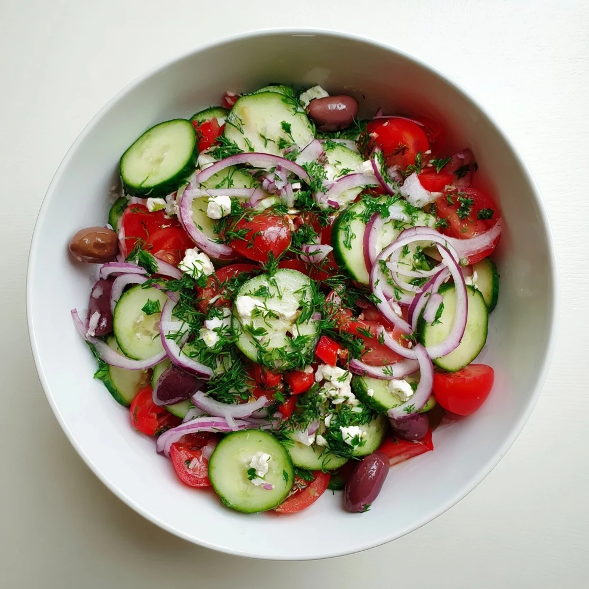Vibrant Mediterranean cucumber salad recipe featuring cherry tomatoes, red onion, and herbs on a rustic wooden table