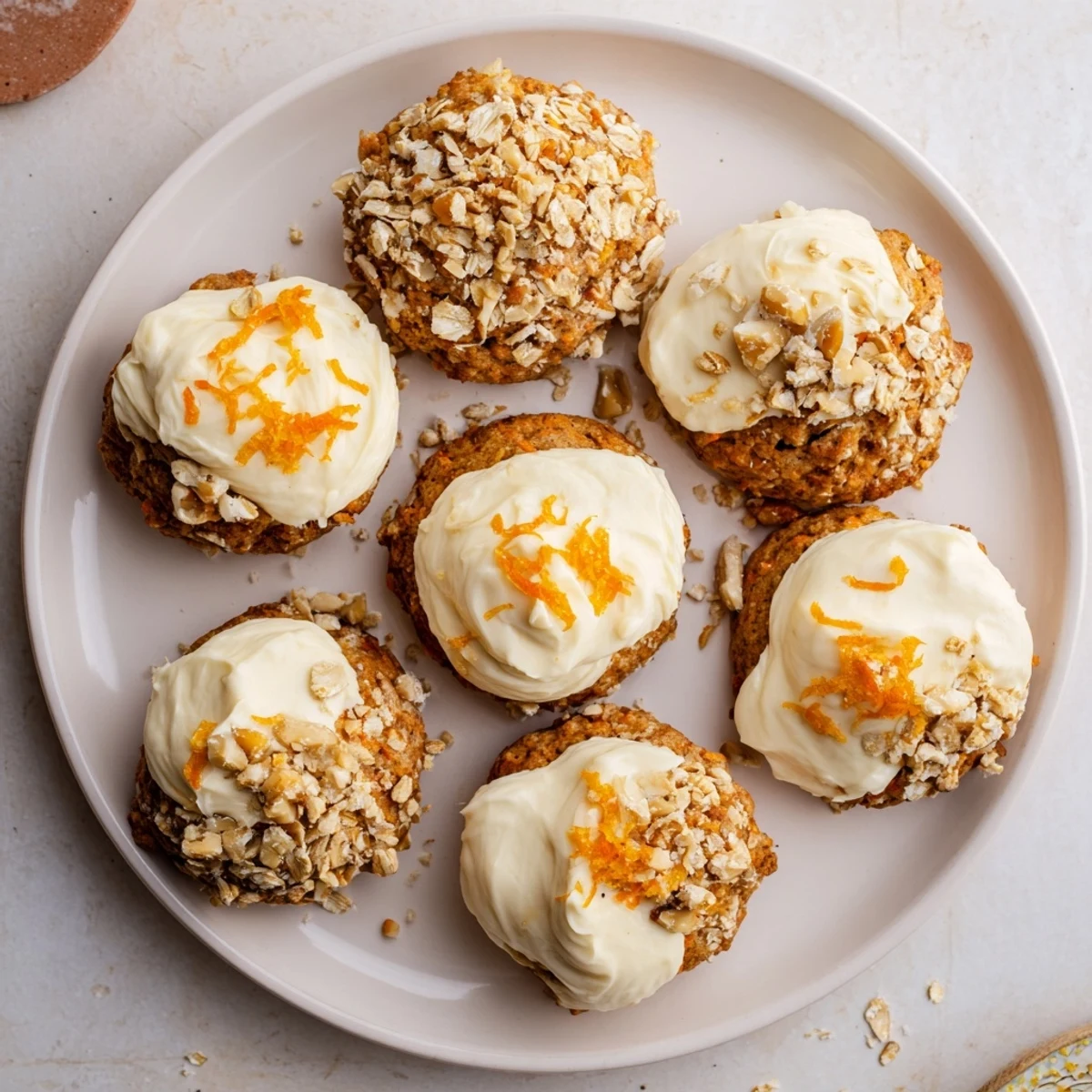 Frosted carrot cake cookies with raisins and pecans displayed on a rustic wooden cutting board