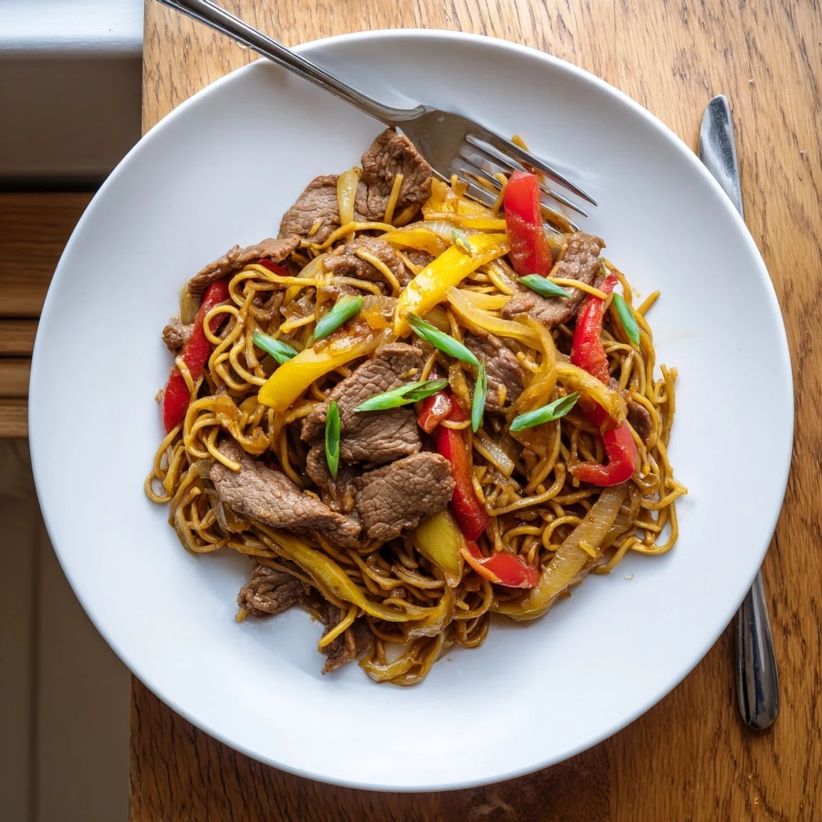 Tender beef stir-fried noodles tossed with crisp bell peppers and sweet caramelized onions
