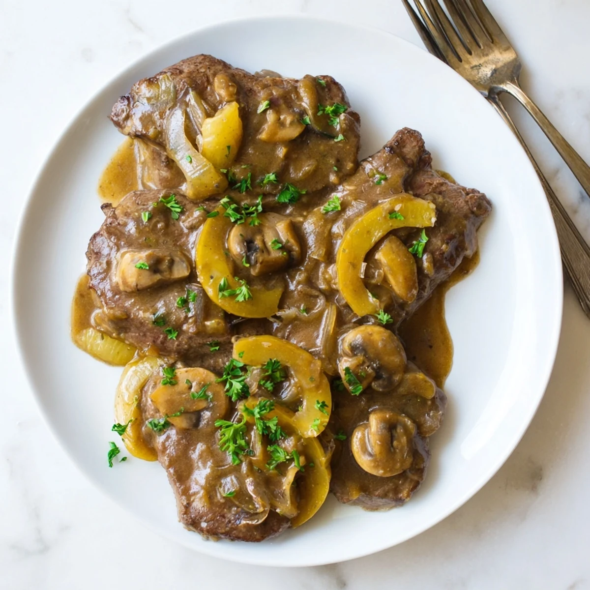 Golden brown country style smothered cube steak served over mashed potatoes with rich onion mushroom gravy