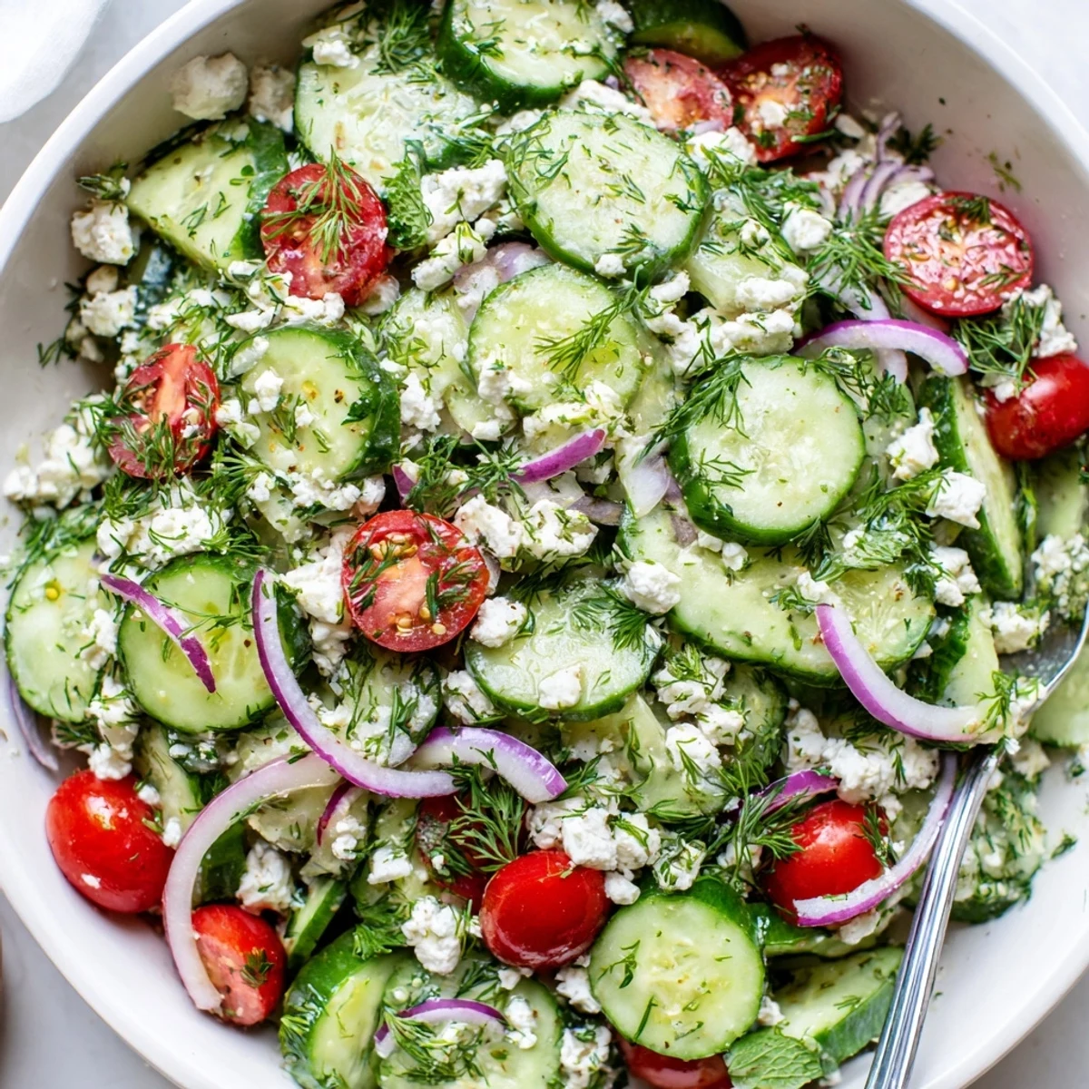Creamy feta tumbles over cool cucumber slices, cherry tomatoes, and fragrant dill in a bright herb salad.