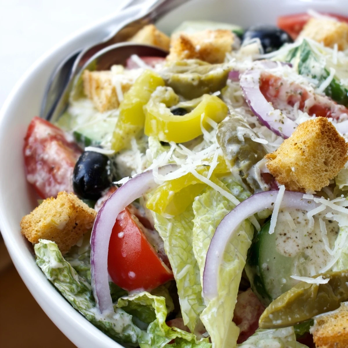 Fresh romaine Olive Garden Salad with tangy pepperoncini, ripe tomatoes, and black olives