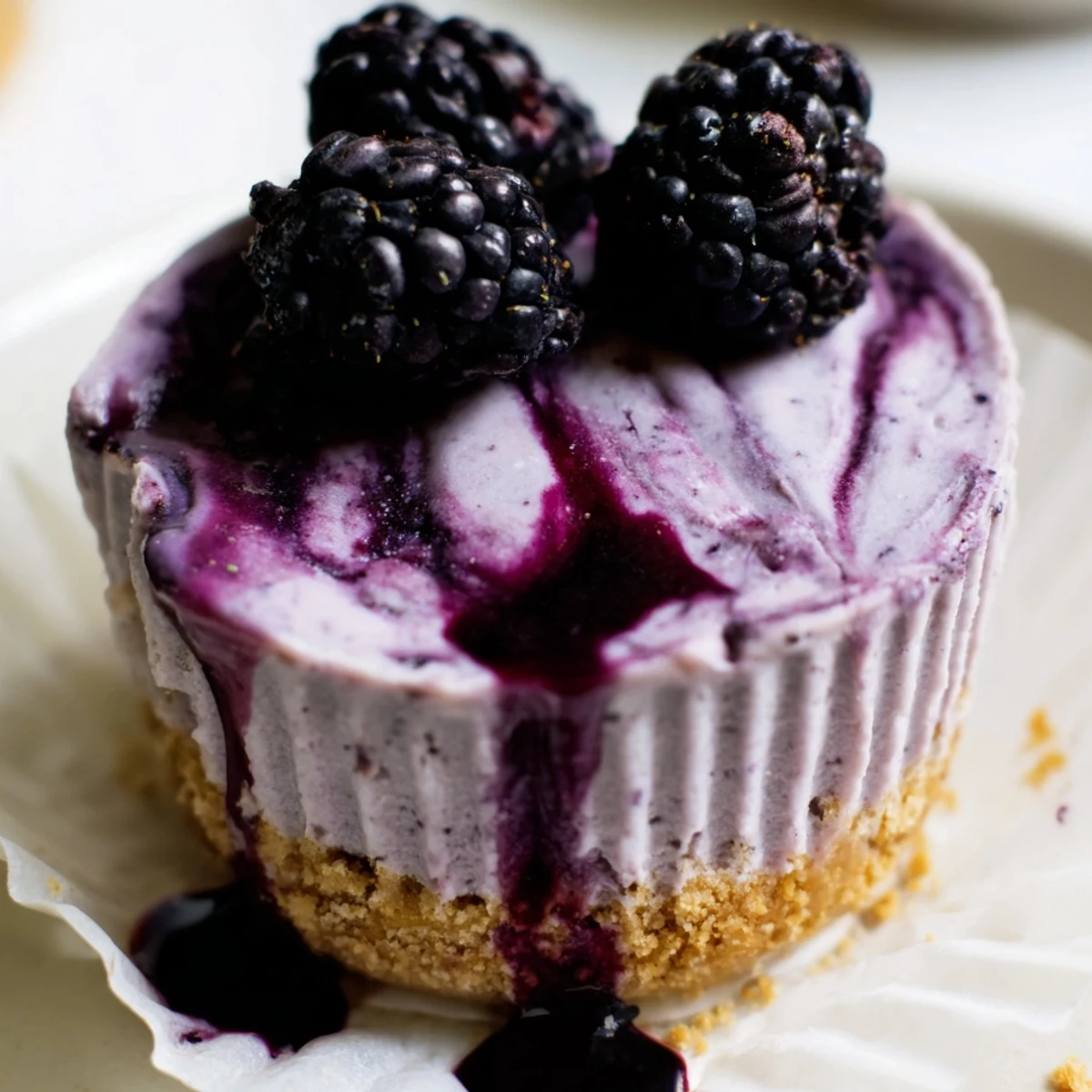 Silky purple-swirled no bake mini blackberry lavender cheesecakes sitting in a buttery graham cracker crust
