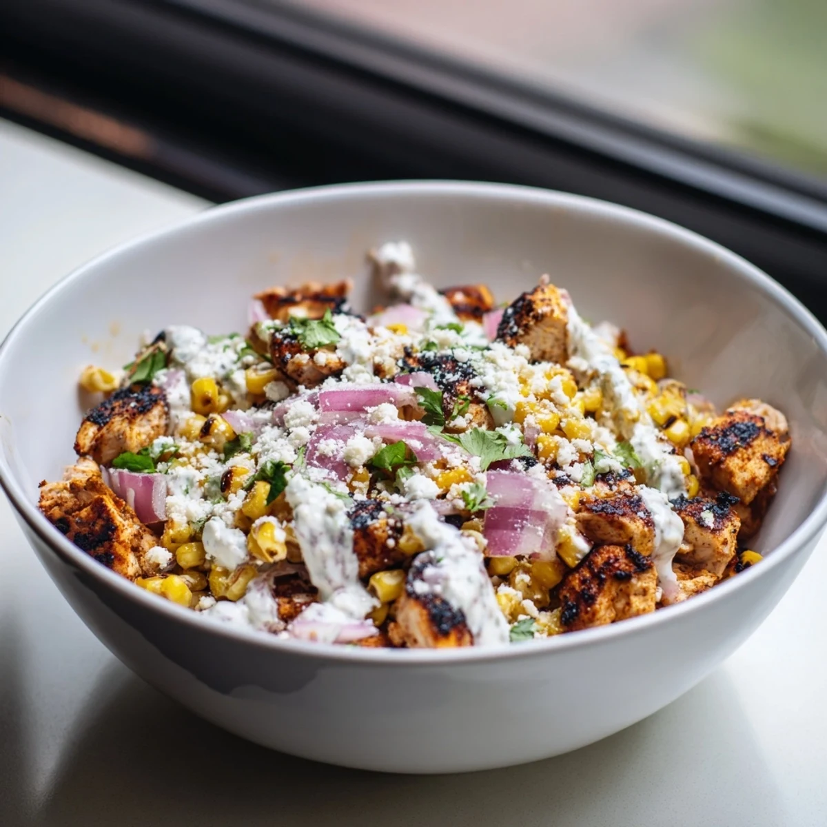 Tasty high protein chicken street corn salad plated with cherry tomatoes, cilantro, and creamy dressing