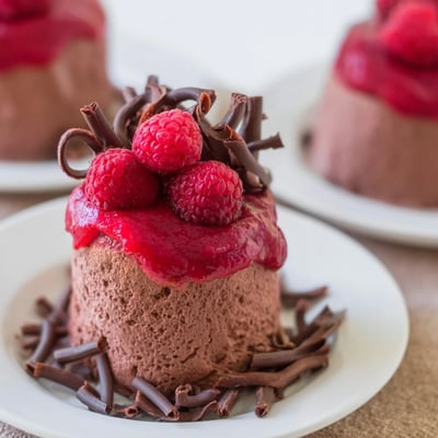 Silky French chocolate mousse topped with a glossy raspberry coulis and a sprinkle of dark chocolate shavings.