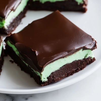 A close-up of Shamrock Mint Brownies with Chocolate Ganache, showing silky ganache topping and a crumbly, chewy interior.