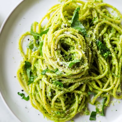 Vibrant green goddess pasta sauce blended with avocado and herbs in a ceramic bowl